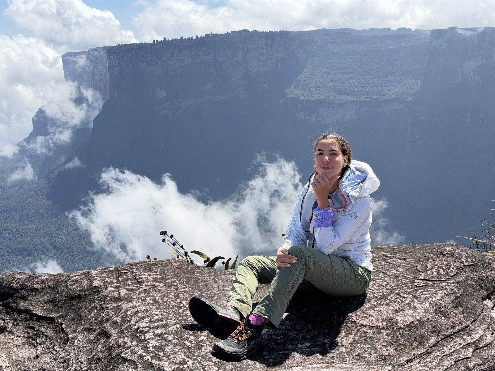 Expedicionario sentado sobre las nubes en la cumbre